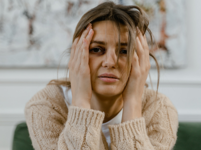 Woman with messy hair who has experienced trauma and is holding her head.